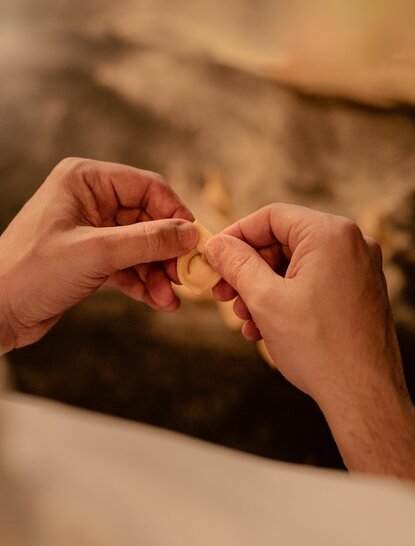 Hands shaping fresh handmade pasta at Aman Nai Lert Bangkok.