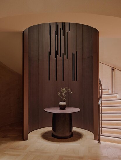 Spa reception area at Aman Rosa Alpina with curved wooden partition, sculptural stone vessel, and minimalist Italian Alpine design.