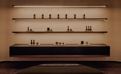 Minimalist spa product display at Aman Rosa Alpina, with bottles and vessels arranged on floating shelves against a warm neutral wall.