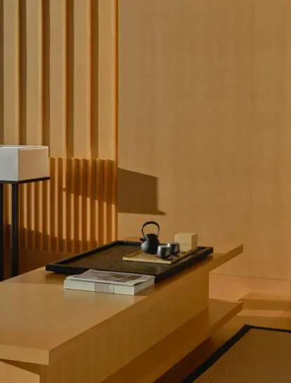 Détail d'une Grand Suite à Aman Tokyo, montrant un bureau en bois clair avec accessoires minimalistes et panneaux en bois vertical en arrière-plan.