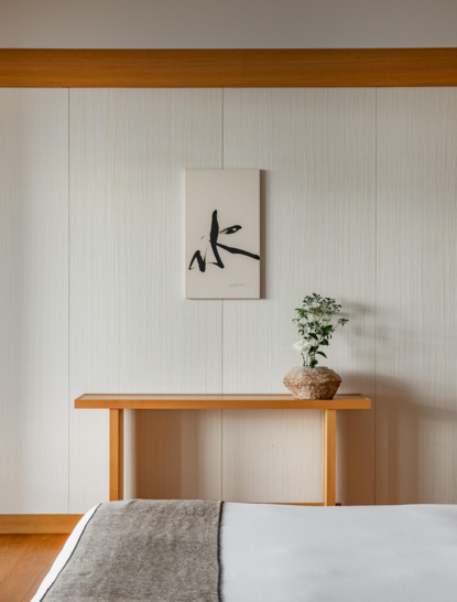 Wooden console table with potted plant and wall-mounted mirror in bedroom at Aman Tokyo hotel.