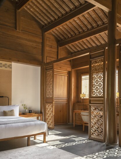 Courtyard suite at Amandayan with carved wooden pavilion, geometric lattice doors, and traditional Chinese architecture.