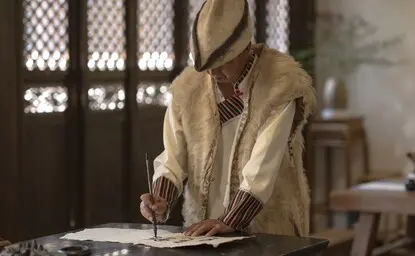 Dongba calligrapher at work in traditional dress at Amandayan, China.