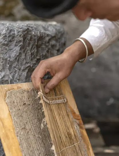 Artisan's hands holding Dongba paper during traditional papermaking at Amandayan, China.
