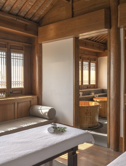 Spa treatment room at Amandayan with wooden architecture, massage table, and warm lighting.