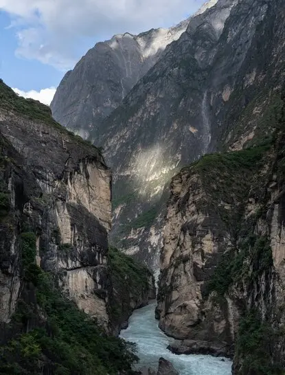 Dramatic gorge with steep limestone cliffs and turquoise river flowing through Tiger Leaping Gorge, Amandayan.