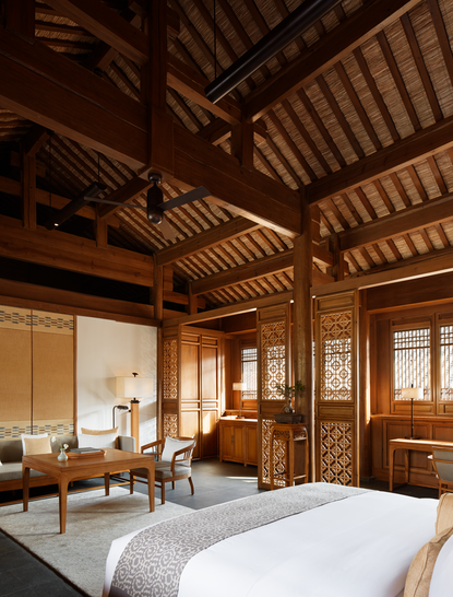 Deluxe Suite bedroom at Amandayan with wooden ceiling beams, traditional architecture, and contemporary furnishings.