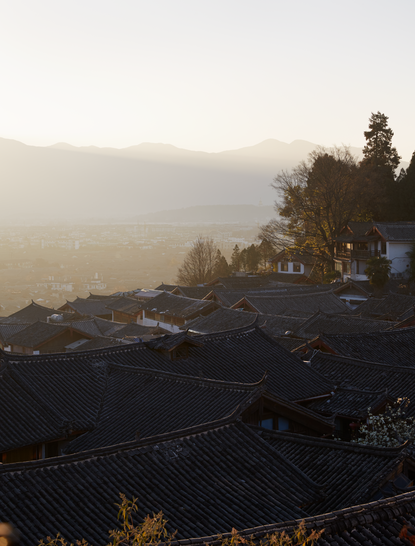 Sunrise over Amandayan's old town, with mist rising above terraced rice fields and forested hills.