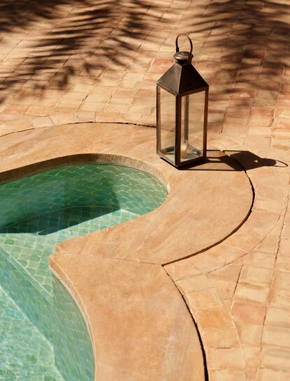 安缦珍纳度假村的游泳池细节，展示曲线形池边和摩洛哥赤土色地面。