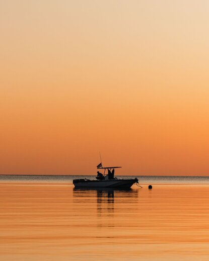 Fishing boat anchored in calm waters at Amanwana at sunset, Indonesia.