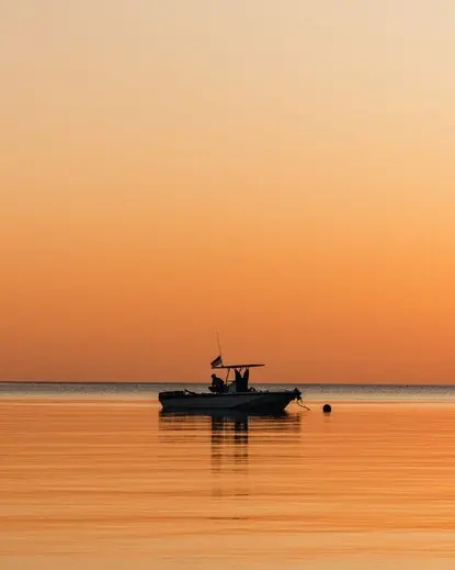 Fishing boat anchored in calm waters at Amanwana at sunset, Indonesia.