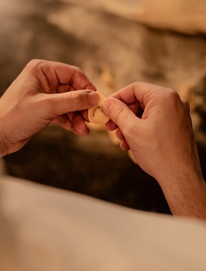 Close-up of hands shaping handmade pasta at Aman Nai Lert Bangkok's dining venue.