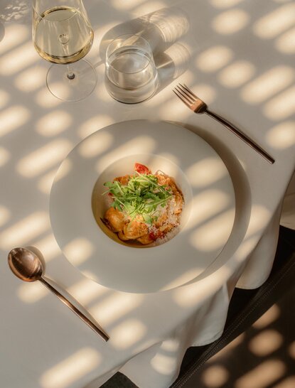 Arva pasta dish served at Amanyangyun, with fresh herbs and garnish, alongside wine glasses and cutlery on white tablecloth.