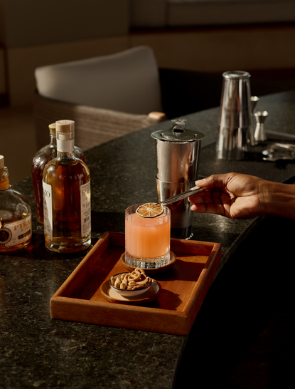 Cocktail bar at Amanyara resort with spirit bottles and a freshly prepared drink on a wooden board.