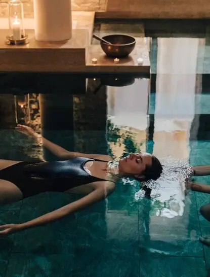 Watsu treatment in a spa pool at Amanzoe, Greece, with therapist guiding guest through warm water therapy.