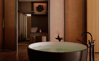 Freestanding oval bathtub with dark tap in a warm-toned bathroom at Aman Nai Lert Bangkok, Premier Suite.