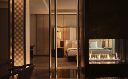 Aman New York entrance with illuminated glass doors opening to a warm, minimalist interior at dusk.