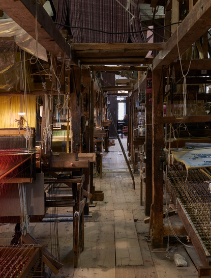 Bevilacqua textile showroom in Venice, with narrow passageway lined by wooden display cases and warm lighting.