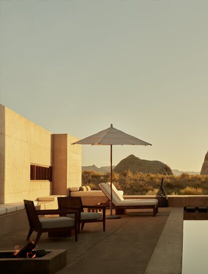 Amangiri Suite with pool terrace at sunset, featuring lounge chairs and umbrella overlooking desert landscape.