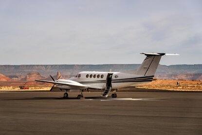 Amangiri's private aircraft on runway with desert landscape and mountains beyond.