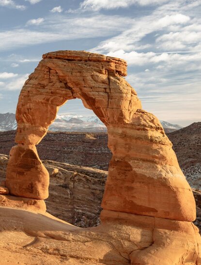 安缦奇岭度假村内，红色砂岩拱门矗立于沙漠景观中，背景为远处山峦。