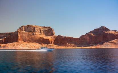Amangiri's clifftop resort overlooks turquoise waters and rust-coloured rock formations under clear sky.