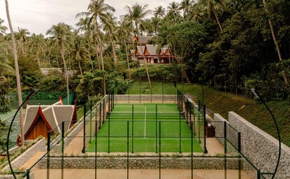 Aerial view of tennis and padel courts at Amanpuri resort, Thailand, surrounded by tropical vegetation.