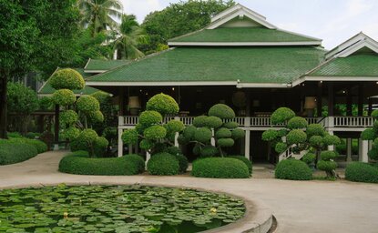 Aman Nai Lert Bangkok's heritage home exterior with manicured topiary and verdant grounds.