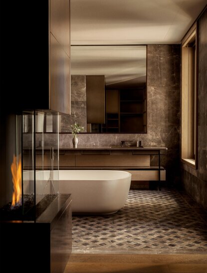 Principal bathroom at Aman New York with marble vanity, geometric floor tiles, and warm lighting.