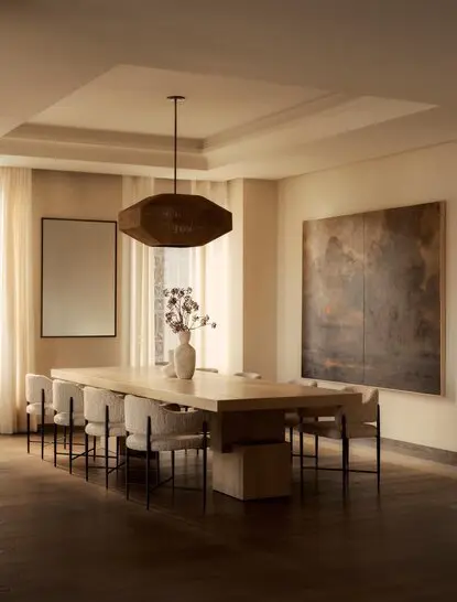 Sala da pranzo della penthouse con tavolo in legno scuro, sedie in rattan e lampadario sospeso presso Aman New York.