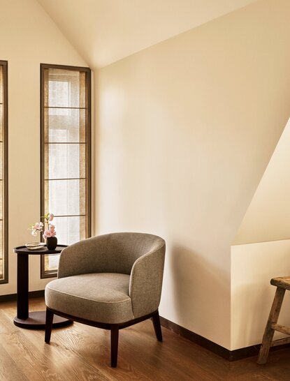 アマン ニューヨークのスリーベッドルームスイート、ベッドルームのコーナーに置かれたベージュのアームチェアと窓。