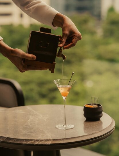 Bartender pouring spirit into a glass at Aman Nai Lert Bangkok, Thailand.