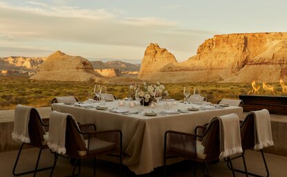 Sala da pranzo privata del resort Amangiri al tramonto, con tavoli eleganti davanti alle formazioni rocciose del deserto.