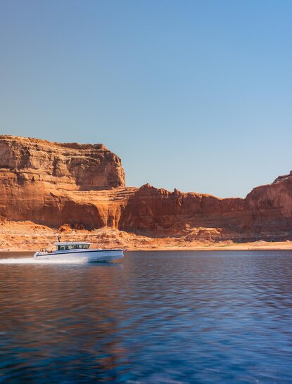 Amangiri's clifftop resort overlooks calm blue waters and rust-coloured rock formations at sunset.