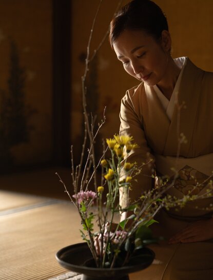 Florist arranging branches and flowers in a shallow bowl at Aman Kyoto, Japanese flower arrangement tradition.