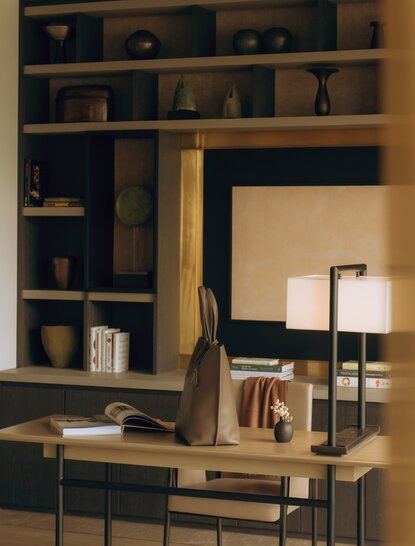 Working desk in an Aman Suite at Aman Nai Lert Bangkok, with shelving and warm lighting.