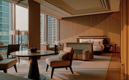 Premier Suite bedroom at Aman Nai Lert Bangkok with warm wood panelling, natural light and contemporary furnishings.