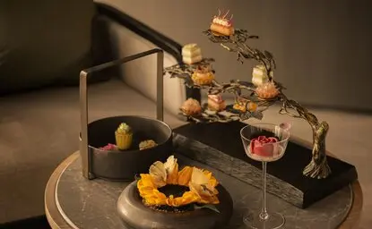 Afternoon tea presentation at Aman Nai Lert Bangkok featuring tiered display with pastries, small bites, and gold-leafed desserts.