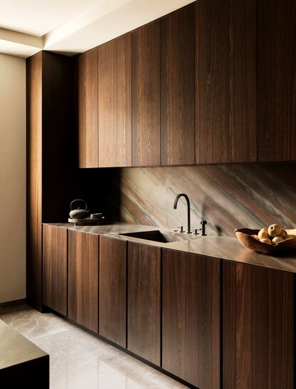 Kitchen at Aman New York with dark wood cabinetry, minimalist sink, and warm lighting.
