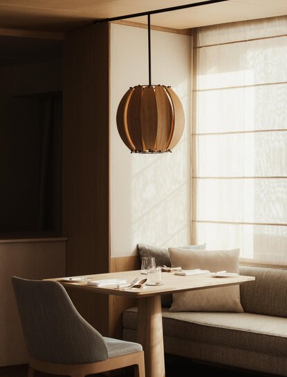 Heritage Room at Aman Rosa Alpina, featuring a dining table by a window with a spherical pendant light.