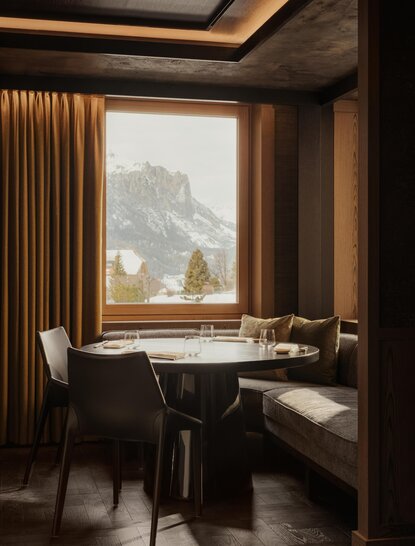 Desk and chair positioned by a window at Aman Rosa Alpina, framing alpine mountain views through warm wood panelling.
