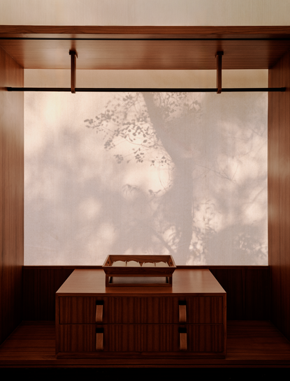 Grand tented pool pavilion at Aman-i-Khas with wooden furniture overlooking garden views through large windows.