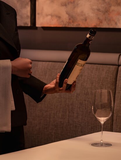 Server pouring wine at Aman Nai Lert Bangkok dining venue.