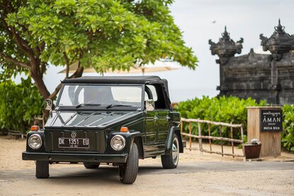 Vintage open-air jeep parked at Aman Villas Nusa Dua, Indonesia, with traditional architecture in background.