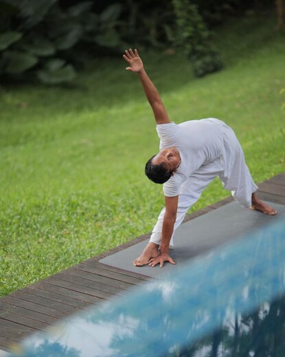 A guest practising yoga in a forward bend position beside a plunge pool at Aman Villas at Nusa Dua, Indonesia.