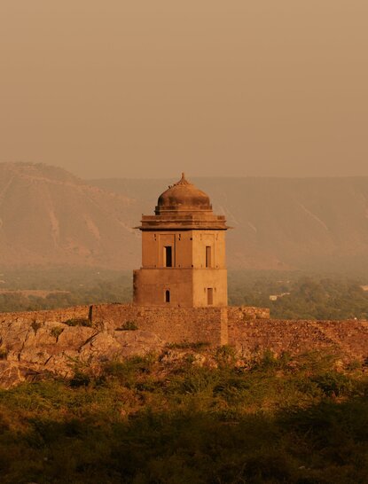 Historic fortification tower at Amanbagh, overlooking the Bhangarh ruins at dusk.