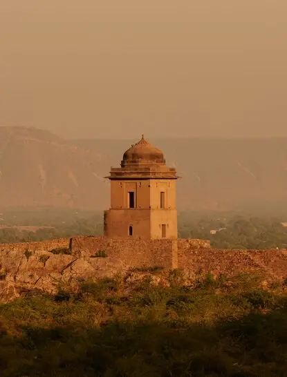 Historic fortification tower at Amanbagh, overlooking the Bhangarh ruins at dusk.