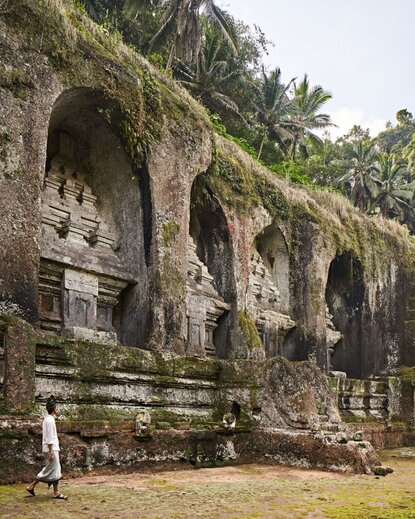 Gunung Kawi temple ruins with ancient stone archways draped in moss and vegetation at Amandari, Bali.