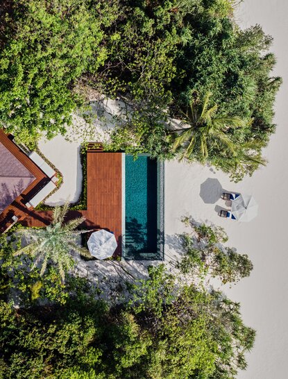 Aerial view of a beachfront casita at Amanpulo with teal plunge pool surrounded by tropical vegetation.