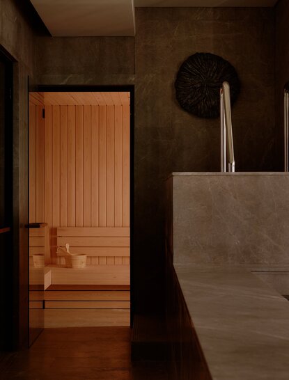 Thermal spa corridor at Aman Nai Lert Bangkok with wooden sauna door and stone sink detail.